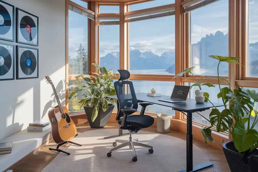 Ergonomische bureaustoel en modern bureau met laptop in lichte kamer met panoramisch uitzicht op bergen.