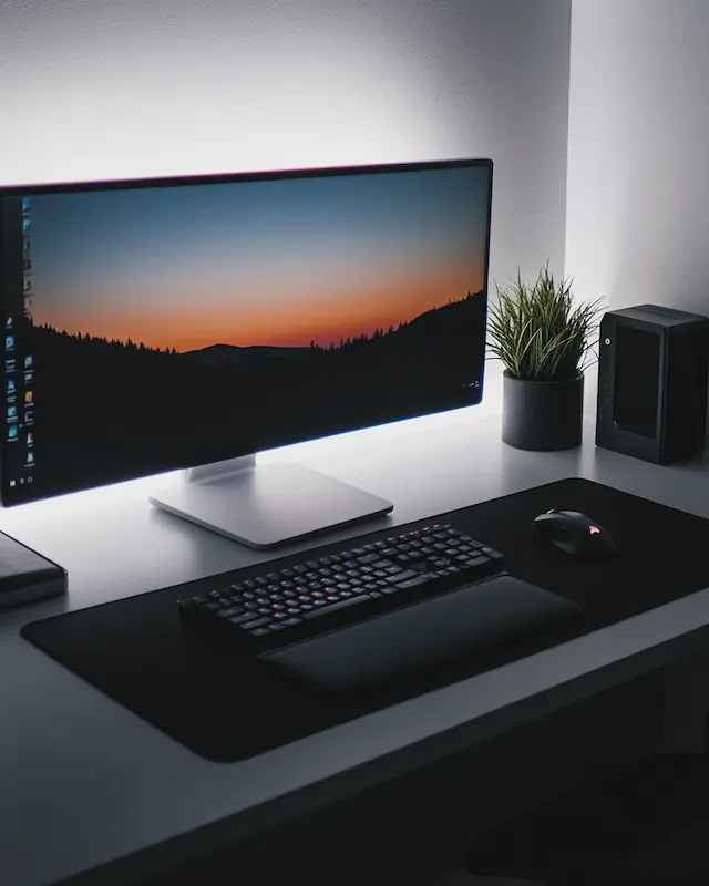 Verlichte monitor met toetsenbord en plantje op een strak ingericht bureau